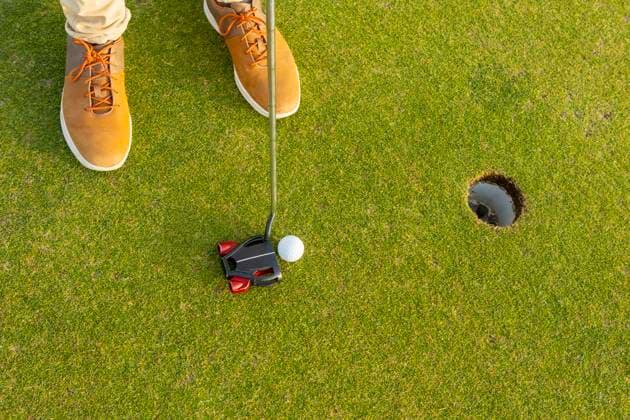 Creative Highlights Symbolbilder From above cropped unrecognizable golfer, sporting a unique pair of brown boots, is about to putt a golf ball into the hole during a tranquil game of golf. Model Released JuanAizpuru_ID20148_596495_024 Copyright: xJuanxAizpurux