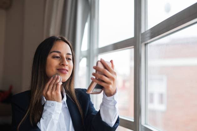 IMAGO Creative, Naturkosmetik Professional woman in a business suit checks her reflection in a compact mirror by a window Model Released PabloMenendez_ID20332_601399_007 Copyright: xPabloxMenendezx RECORD DATE NOT STATED