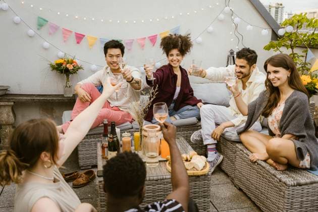 Group of multiracial friends toasting drinks while sitting together in balcony Germany, Berlin, model released, property released Copyright: xMaskotx , MA108150 MA108150