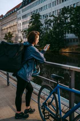 Female delivery person using smart phone while leaning on railing by bicycle on footpath Germany, Berlin, model released Copyright: xMaskotx , MA108246 MA108246
