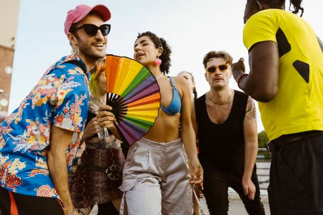 Non-binary person holding hand fan and dancing with multiracial friends in city Germany, Berlin, model released Copyright: xMaskotx , MA108332 MA108332