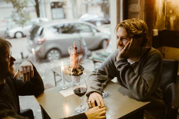 Smiling gay man leaning on elbow while talking with boyfriend sitting at restaurant Germany, Berlin, model released, property released Copyright: xMaskotx , MA108441 MA108441