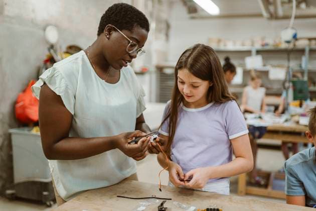 Female teacher explaining electrical part to student at technology workshop in classroom Germany, Berlin, model released, property released Copyright: xMaskotx , MA108567 MA108567