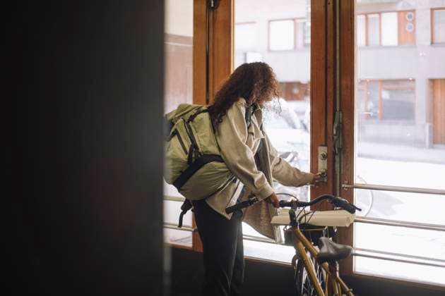 Side view of female freelancer opening door while leaving from building with bicycle Sweden, Stockholm, model released Copyright: xMaskotx , MA108706 MA108706