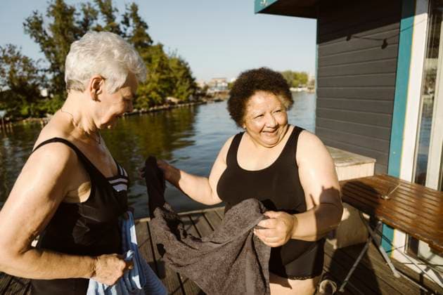 Happy senior female friends holding towel while standing on houseboat at sunny day Germany, Berlin, model released, property released Copyright: xMaskotx , MA108714 MA108714
