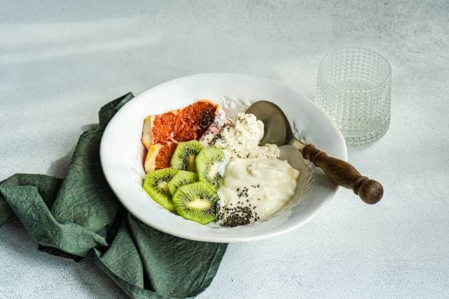 A well-balanced breakfast setting featuring a white bowl with cottage cheese, natural yogurt, and chia seeds, accompanied by kiwi and Sicilian orange slices Model Released AnnaBogush_ID20662_610159_010 Copyright: xAnnaxBogushx