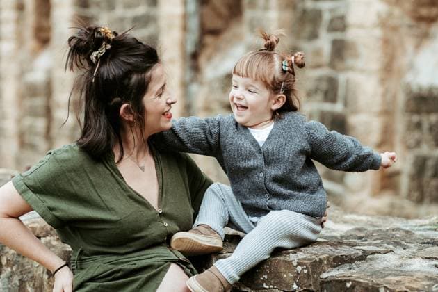 A heartwarming scene of a mother and child sharing a laugh while sitting on a rustic stone ledge in casual wear Model Released HodeiUnzueta_ID20569_607707_019 Copyright: xHodeixUnzuetax