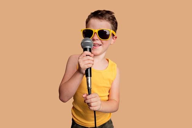 Creative Highlights Symbolbilder Young boy in a yellow tank top and sunglasses singing into a microphone against a beige background Model Released HodeiUnzueta_ID20903_616924_011 Copyright: xHodeixUnzuetax
