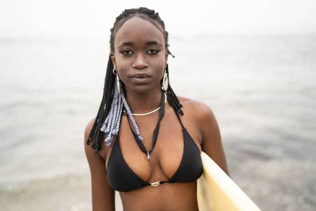Creative Highlights Symbolbilder An African American woman with braided hair wearing a black bikini stands confidently at the beach, holding a surfboard and exuding a sense of calmness Model Released OscarDeDios_ID20936_617656_011 Copyright: xOscarxDexDiosx RECORD DATE NOT STATED