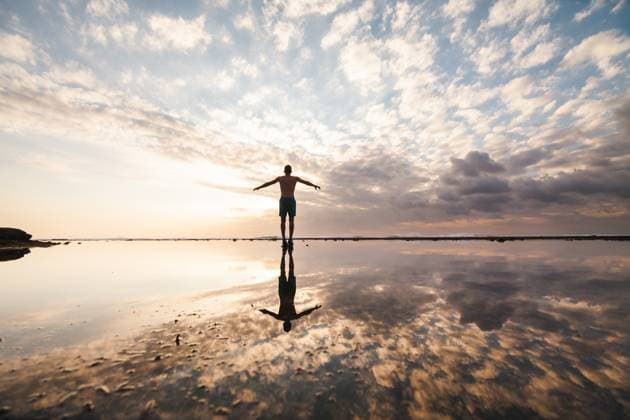Creative Highlights Symbolbilder Silhouette of a person with arms outstretched on a reflective beach at sunset, under a cloudy sky in Indonesia Model Released PabloMenendez_ID19741_585392_067 Copyright: xPabloxMenendezx RECORD DATE NOT STATED
