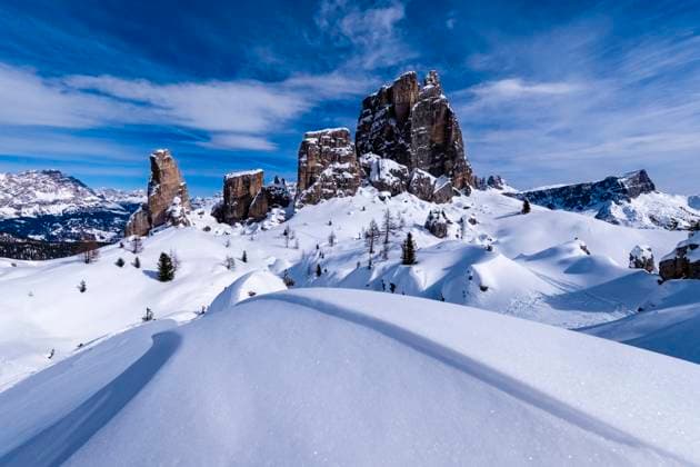 Snowdrift creating artful structures in winter, snow-covered slopes of alpine Dolomite landscape and summits of the Cinque Torri group in the distance. Cortina d˜Ampezzo Veneto Italy FB_2024_1005