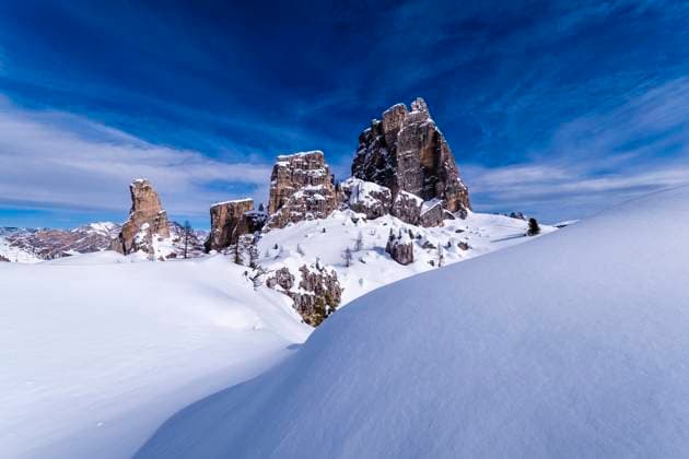 Snowdrift creating artful structures in winter, snow-covered slopes of alpine Dolomite landscape and summits of the Cinque Torri group in the distance. Cortina d˜Ampezzo Veneto Italy FB_2024_1011