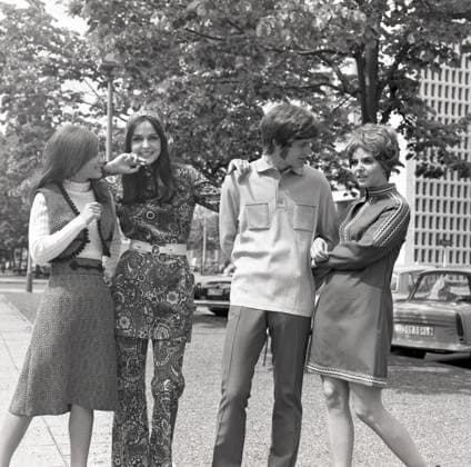 01.07.1971, Berlin, DDR - Werbeaufnahme fuer Modezeitschriften: Models zeigen in der Stadt die neueste Herbst-Mode. (20-30 Jahre, 70er Jahre, Alltag, aussen, Aussenaufnahme, befreundet, Bekleidung, Berlin, Damenmode, DDR, deutsch, Deutsche Demokratische Republik, Deutschland, Europa, europaeisch, Fashion, Frauen, Freunde, Fuer Dich, GDR, Gesellschaft, Herrenmode, Historie, historisch, Jahreszeit, Kaukasier, kaukasisch, Kleider, Kleidung, Mann, Mannequins, Menschen, Mode, Modeaufnahme, Modekollektion, Models, Modeshooting, modisch, Personen, pmscartandhistory, praesentieren, Pramo, Pullover, QF, Quadrat, Querformat, s w, schwarz weiss, schwarz-weiss, Schwarzweiss, Sibylle, Siebziger Jahre, Sommer, Stadt, Stadtleben, Strasse, Strassenszene, W