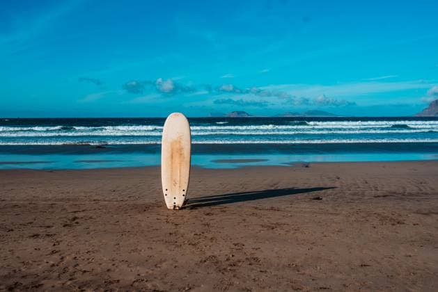 Surfboard in sand on a sunny beach during sunset. Surfboard stucked in sand on a sunny beach during sunset. model released