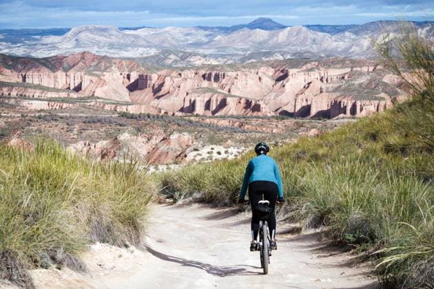 Cyclist woman riding into desert canyon. Granada, Andalusia, Spain CR_VZNFTC240411-1394716-01 ,model released, Symbolfoto