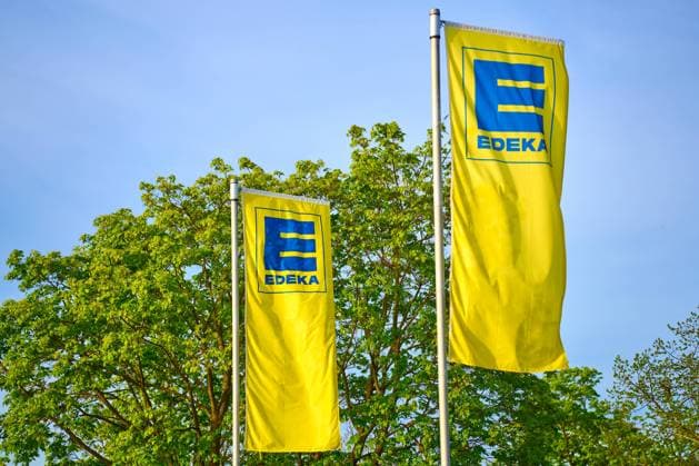 Fahne vom deutchen Supermarkt und Lebensmittelhändler EDEKA vor grünen Bäumen