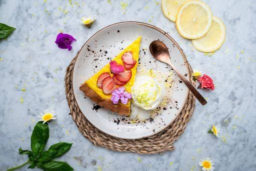 A plate with Vegan No-bake cheesecake topped with strawberry on the side cashew cream. Served on a plate with fruits around. 23149080 RECORD DATE NOT STATED