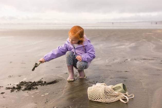 Creative Highlights Symbolbilder Red head girl digs in sand at beach Seabrook, Washington, United States R_PXQG240415-1397331-01 ,model released, Symbolfoto