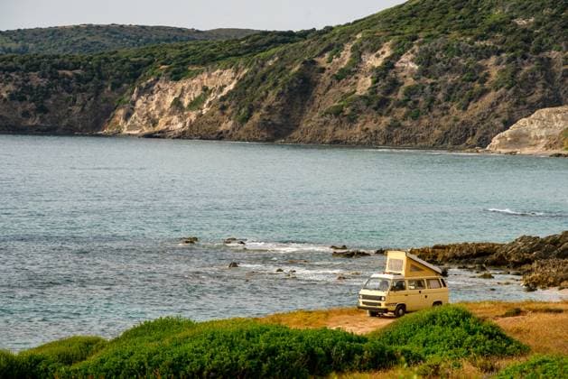 Old retro yellow camper van near the sea on a wild landscape Magazzini, Sardegna, Italy CR_UGOUSD240415-1391163-01