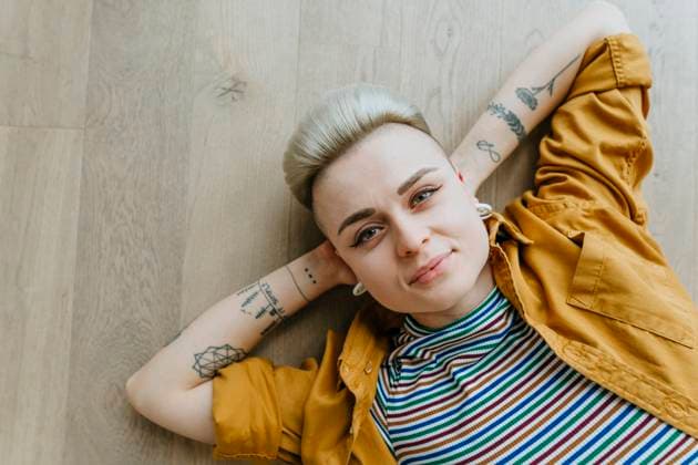 Creative Highlights Symbolbilder Smiling woman with tattoos lying down on floor at home model released, Symbolfoto property released, YTF02083