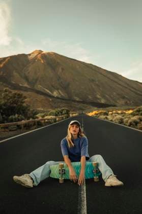 Creative Highlights Symbolbilder Carefree woman sitting with skateboard on mountain road in front of Mount Teide model released, Symbolfoto, ACPF01580