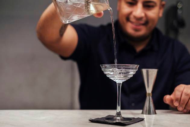 Bartender pouring cocktail in glass at bar counter model released, Symbolfoto property released, ASGF05046