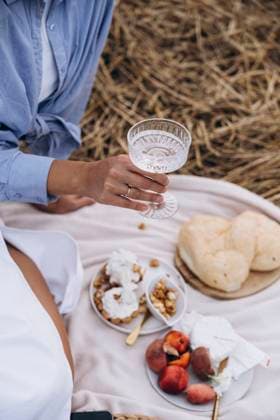 Hand of woman holding glass of water with snacks on picnic blanket model released, Symbolfoto, KANF00061