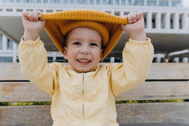 Creative Highlights Symbolbilder Smiling boy pulling orange knit hat model released, Symbolfoto, KVBF00108