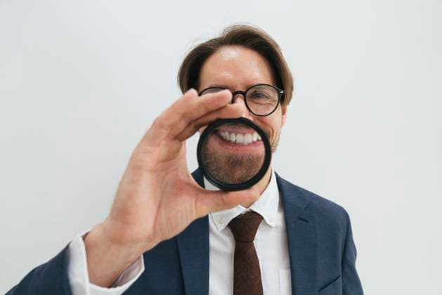 Creative Highlights Symbolbilder Smiling businessman looking through magnifying glass against white background model released, Symbolfoto property released, VPIF09308