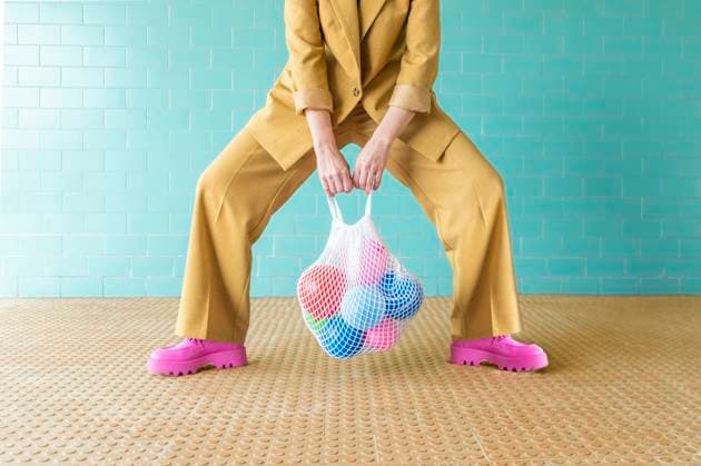 Creative Highlights Symbolbilder Woman holding mesh bag with colorful balloons near turquoise wall model released, Symbolfoto, VRAF00498