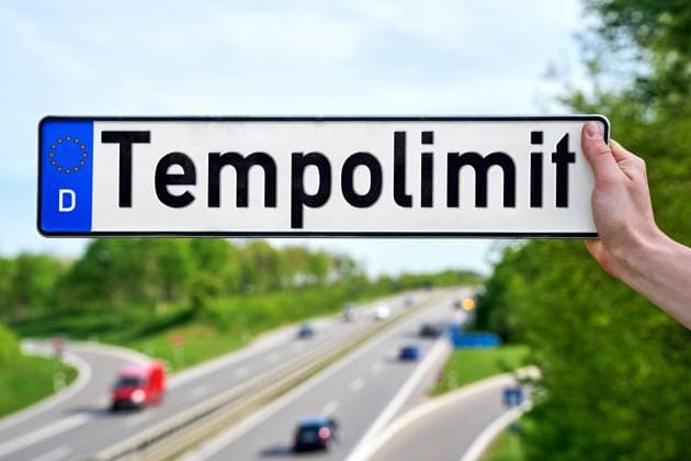 April 25, 2024: Hand holds a license plate in front of a highway with the inscription: Speed limit. PHOTOMONTAGE *** Hand hält vor eine Autobahn ein Kfz-Kennzeichen mit Aufschrift: Tempolimit. FOTOMONTAGE