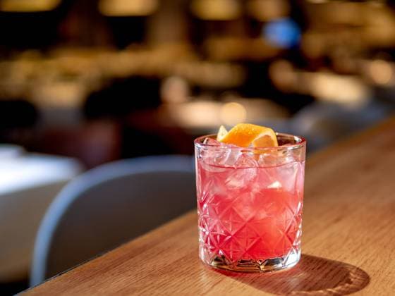 Transparent pink alcohol cocktail, vodka gin-tonic Transparent pink alcohol cocktail with ice, aperol and gin on bar counter in restaurant interior. Alcohol cocktail decorated orange zest spiral. Cold alcoholic cocktail in bar or nightclub. Copy space Copyright: xZoonar.com OlgaxSergeevax 21392651