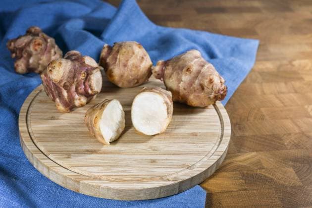 Root vegetable Jerusalem artichoke or topinambur (Helianthus tuberosus), whole and halved on a rustic wooden kitchen board and a blue napkin, for healthy diet and diabetes, copy space Root vegetable Jerusalem artichoke or topinambur (Helianthus tuberosus), whole and halved on a rustic wooden kitchen board and a blue napkin, for healthy diet and diabetes, copy space, selected focus Copyright: xZoonar.com MarenxWinterx 21524783