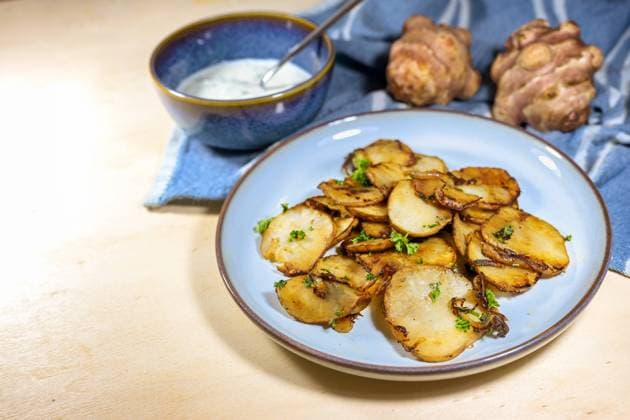 Crispy fried slices of Jerusalem artichoke or topinambur (Helianthus tuberosus) with onions and parsley on a blue plate with a fresh dip, healthy root vegetable, copy space Crispy fried slices of Jerusalem artichoke or topinambur (Helianthus tuberosus) with onions and parsley on a blue plate with a fresh dip, healthy root vegetable, copy space, selected focus Copyright: xZoonar.com MarenxWinterx 21524793