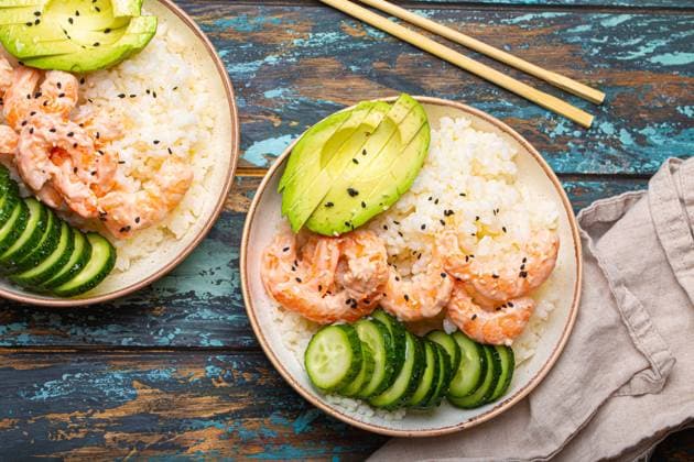 Two white ceramic bowls with rice, shrimps, avocado, vegetables and sesame seeds and chopsticks on colourful rustic wooden background top view. Healthy asian style poke bowl Two white ceramic bowls with rice, shrimps, avocado, vegetables and sesame seeds and chopsticks on colourful rustic wooden background top view. Healthy asian style poke bowl. Copyright: xZoonar.com OlenaxYeromenkox 21585610
