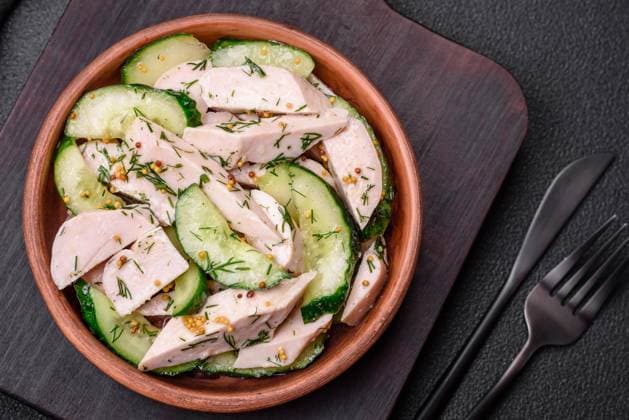 Delicious juicy fresh salad of cucumbers and grilled chicken slices, with french mustard Delicious juicy fresh salad of cucumbers and grilled chicken slices, with french mustard, salt and spices on a dark concrete background Copyright: xZoonar.com TetianaxChernykovax 21588520