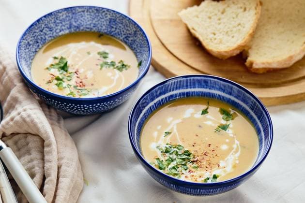 IMAGO Creative, Herbst, Wärmende Suppen und Eintöpfe Two bowls of creamy potato soup, spoons, napkin and wooden cutting board with a loaf of bread and cut pieces. The surface of the soup is decorated with cream, croutons, parsley and ground red pepper. Two bowls of creamy potato soup, spoons, napkin and wooden cutting board with a loaf of bread and cut pieces. The surface of the soup is decorated with cream, croutons, parsley and ground red pepper. Copyright: xZoonar.com BurakovaxIrinax 21589664