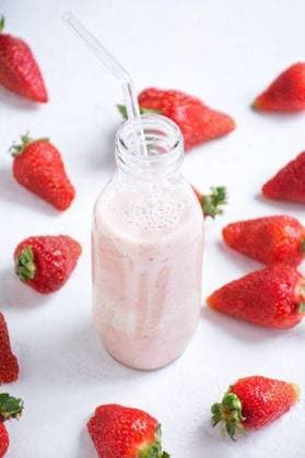 A glass bottle filled with strawberry-flavored milk surrounded by fresh strawberries 24436681 RECORD DATE NOT STATED