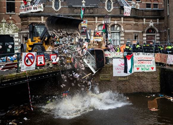 Bilder des Jahres 2024, News 05 Mai News Themen der Woche KW19 News Bilder des Tages AMSTERDAM - A police shovel throws rubble from the barricades into a canal near the Binnengasthuis grounds of the University of Amsterdam (UvA). Entrances to the site were blocked from several sides with, among other things, pallets and bicycle racks. The demonstrators were protesting in solidarity with pro-Palestinian students who were removed by police during protests at the Roeterseiland campus. ANP RAMON VAN FLYMEN netherlands out - belgium out  Copyright: xx x497953741x originalFilename: 497953741.jpg