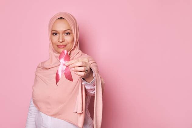 Pink satin ribbon in hands of Muslim woman, showing support for cancer survivors. October 1st, awareness month campaign Selective focus on pink satin ribbon in hands of blurred Muslim pretty woman, showing support for cancer survivors, isolated on pink background with copy space. Pink October, awareness month campaign Copyright: xTarasxGrebinets RECORD DATE NOT STATED