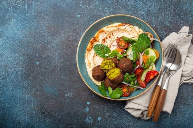 IMAGO Creative, Food, Hummus Middle Eastern Arab meal with fried falafel, hummus, vegetables salad space for text Middle Eastern Arab meal with fried falafel, hummus, vegetables salad with fresh green cilantro and mint leaves in ceramic bowl on stone rustic background top view. Arabic cuisine, space for text Copyright: x RECORD DATE NOT STATED