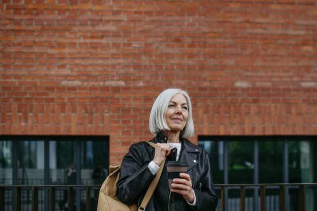 Portrait of stylish mature woman with gray hair on city street. Older woman in leather jacket with soft smile. Portrait of stylish mature woman with gray hair on city street, outdoor. Older woman in leather jacket with soft smile on face. model released