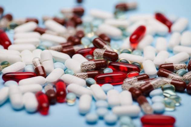 Background of multi-colored medical pills and translucent gel capsules, isolated blue backdrop. Pharmaceutical industry Background of multi-colored medical pills, tablets, dragees and translucent gel capsules, scattered on blue background. Close-up. Still life. Pharma business. Pharmaceutical industry. World Health Day Copyright: xTarasxGrebinets RECORD DATE NOT STATED