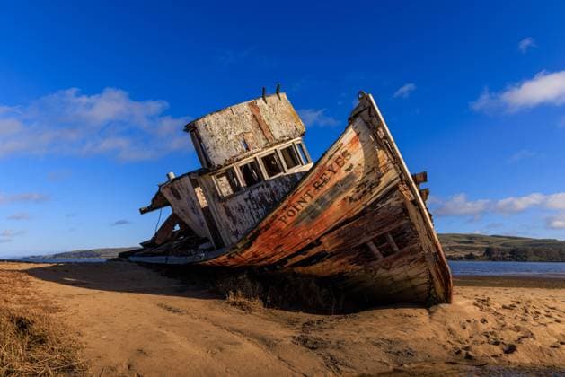 Historic wooden fishing boat wreck on sandy beach in sun and blue sky Historic wooden fishing boat wreck on sandy beach in sun and blue sky. High quality photo Copyright: x RECORD DATE NOT STATED