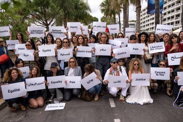 Cannes - Guerrieres De La Paix Flash Mob Action for Gaza and Israel Moroccan Belgian actress Loubna Azabal (first from L) and producer Lamia Chraibi (2nd from L) and other women from ?Women warriors of peace? carry messages in French, Arabic, Hebrew and English stating ?Peace?, ?Cease Fire?, Release the Hostages?, demonstrate on the ?Croisette? in Cannes, to draw attention to the situation in Gaza and Israel, around the 77th Cannes Film Festival, in Cannes, France, on May 20, 2024. Photo by Ammar Abd Rabbo ABACAPRESS.COM Cannes France Copyright: xABACAx