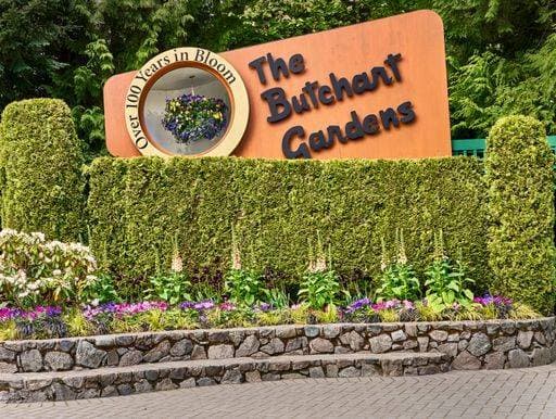 Close-up of the bright orange entrance sign behind a bed of flowers at the Butchart Gardens Victoria, BC. 24596352