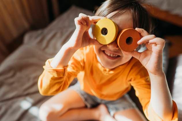 Creative Highlights Symbolbilder Happy boy looking through toy sitting on bed at home model released, Symbolfoto property released, ANAF02812