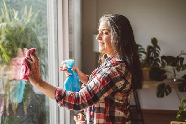 IMAGO Creative, Frühling, Frühjahrsputz Mature woman cleaning window glass with rag at home model released, Symbolfoto property released, JCCMF11496