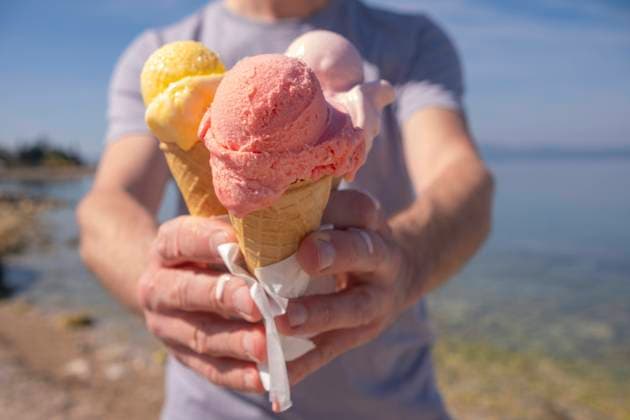 Man holding colorful ice cream in waffle cups on sunny day at seashore model released, Symbolfoto, KVBF00119