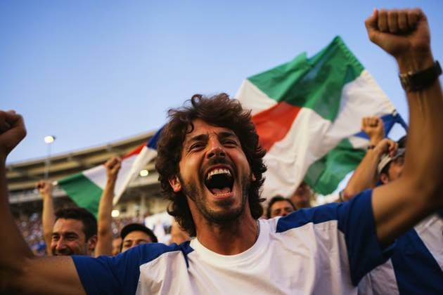 A diverse group of people from Italy wave flags enthusiastically and shout in celebration, creating a dynamic scene of unity and enthusiasm. Model Released AdalbertoRodriguez_ID21413_629946_013 Copyright: xAdalbertoxRodriguezx RECORD DATE NOT STATED